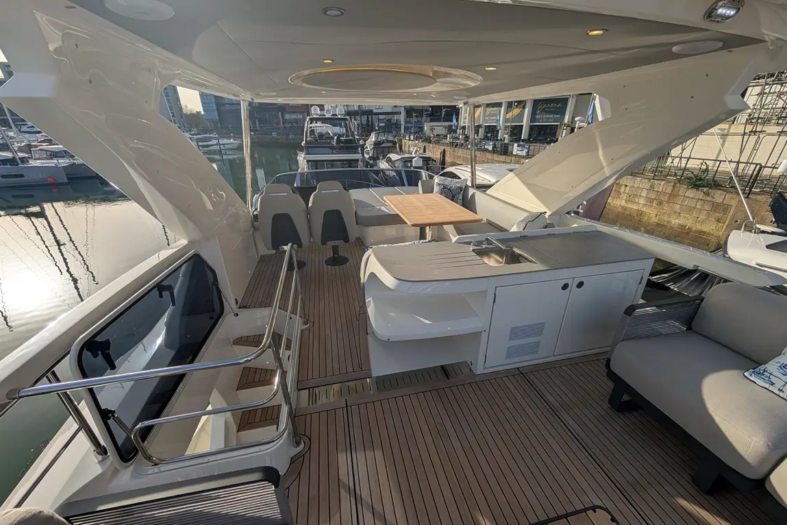 Luxury yacht interior featuring a galley, dining area, and seating by the water, with marina views and modern furnishings.
